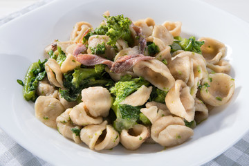 Traditional dish of Apulia region pasta Orecchiette with turnip greens and salted anchovies, top view, clous-up
