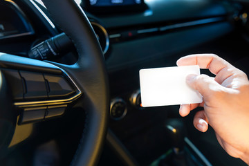 Driver in car hold a blank business card or driver license card