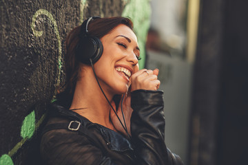 Young woman enjoys music via headphones on the street