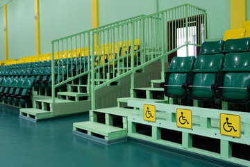 Green and yellow seats and seats for the disabled. Seating seats sports hall. Free space. Territory without people.