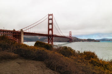 Beautiful view of Golden Gate Bridge, foggy sky and beautiful trees and shrubs in blossom