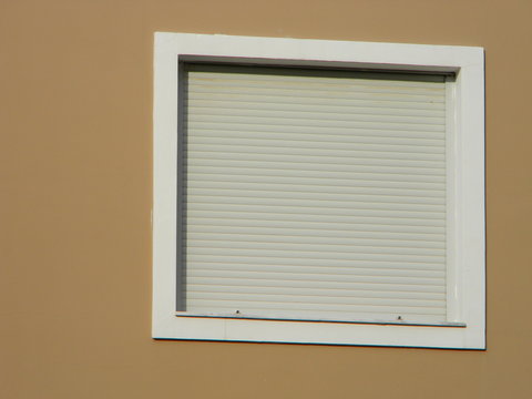 A closed white rolling shutter under bright sunlight