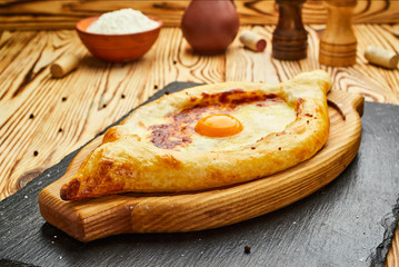 Ajarian Khachapuri traditional Georgian cheese pastry with eggs on cutting board. Homemade baking. Open pie with mozzarella