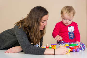 Naklejka premium Mother playing with her daughter with wooden toys at the table.