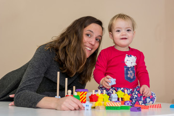 Fototapeta premium Mother playing with her daughter with wooden toys at the table.