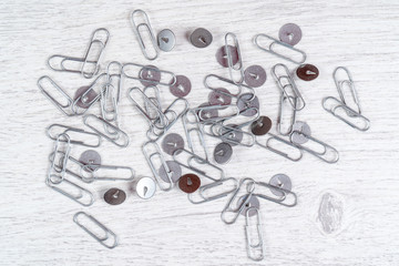 Fototapeta premium Metal push pins and paperclips scattered on grey wooden background