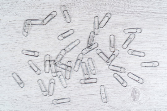 Paper clips scattered on a gray wooden surface