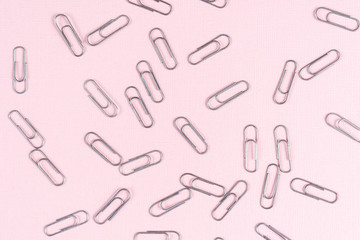 Paper clips scattered on a pink sheet of paper