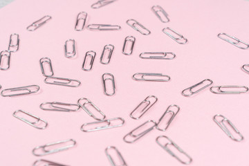 Paper clips scattered on a pink sheet of paper