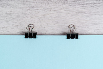 Binder clip holds a blue sheet of paper