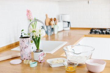Baking ingredients placed on wooden table, ready for cooking. Concept of food preparation, white kitchen on background.
