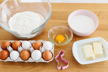Baking ingredients placed on wooden table, ready for cooking. Concept of food preparation, white kitchen on background.