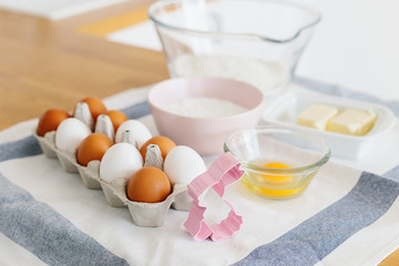 Baking ingredients placed on wooden table, ready for cooking. Concept of food preparation, white kitchen on background.