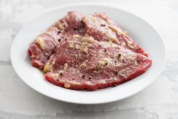 raw meat with spices on white dish