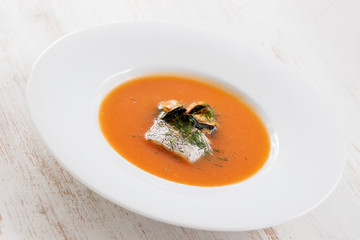 fish soup in white plate on white wooden background