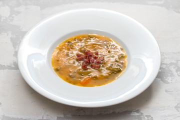 soup with smoked meat in white plate on ceramic dish