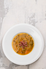 soup with smoked meat in white plate on ceramic dish