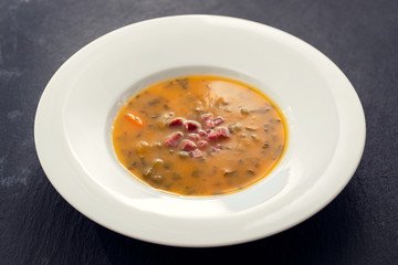 soup with smoked meat in white plate on ceramic dish
