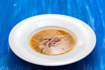 soup with smoked meat in white plate on wooden dish