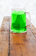 Full fresh cold glass of green beer on wooden bench