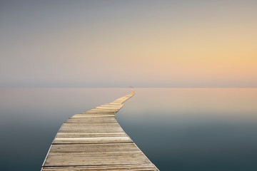 landscape with calm sea and long wharf at sunset