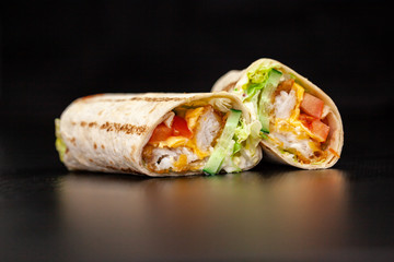 Shawarma sandwich gyro- fresh roll of thin lavash (pita bread) filled with grilled meat, mushrooms, cheese, cabbage, carrots, sauce, green. Traditional Eastern snack. On a wooden background