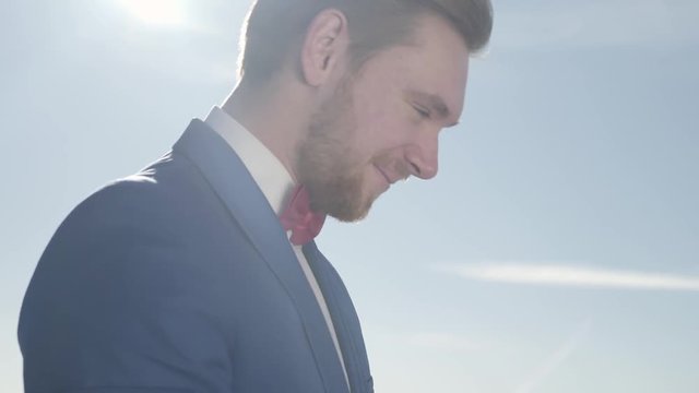 Young blond happy woman fixing bow tie of young handsome smileing berded man in classical blue suit
