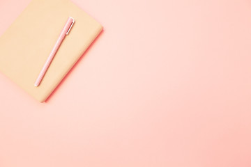 Beige diary with pink pen on pastel millennial pink paper background. Concept of education, blogging. Top view. Flat lay. Minimal style. Template for female blog. Lifestyle. Copy space