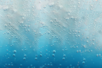 Close-up bubbles of the blue soda and ice cubes 