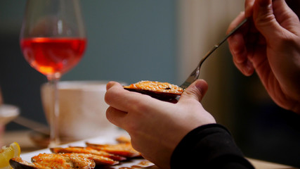 Cooked mussels. A person eating the mussel with a fork