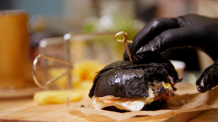 Bitten black burger with bacon and bbq sauce on a wooden desk