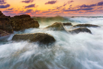 Beautiful natural seascape wave moving on the rock during sunrise