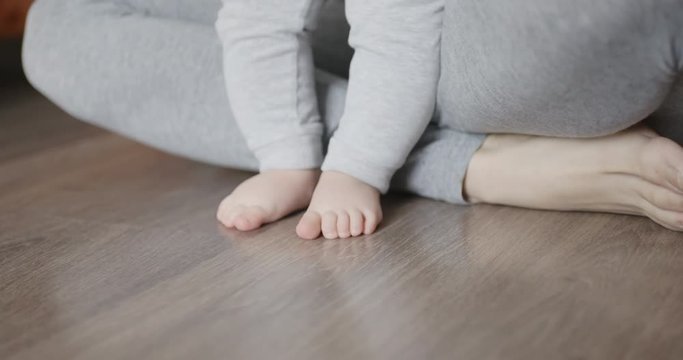 Mother assisting in her baby first steps in living room.
