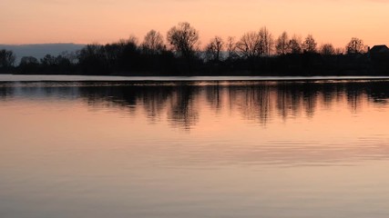 red sunset over the water of a village lake