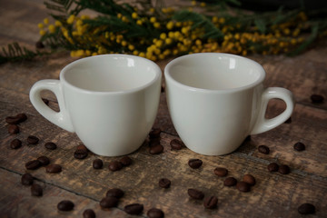 Coffee cups with coffee beans and a sprig of mimosa