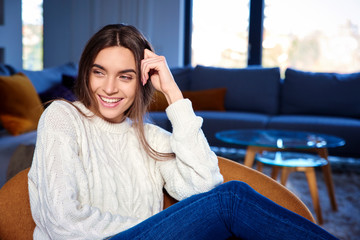 Happy young woman relaxing on sofa at home in the morning
