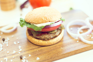 Closeup of delicious fresh homemade hamburger on wooden background.