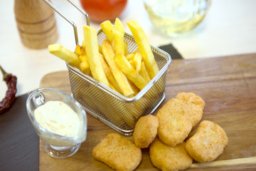 Chicken nuggets and french fries on wooden background