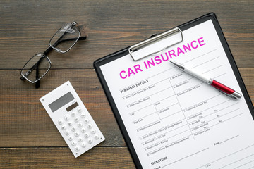 Car insurance form near glasses, calculator, pen on dark wooden background top view