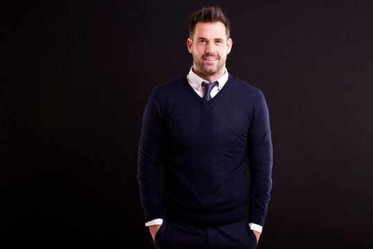 Portrait of handsome man looking at camera and smiling while standing at isolated black bacgkround