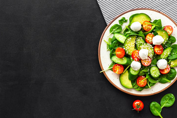 Healthy lunch. Fresh vegetable salad on black background top view copy space