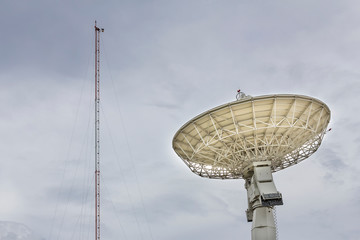 High technology satellite dish or radio telescopes station and radio antenna pole on cloudy sky day