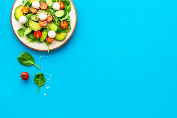 Healthy lunch. Fresh vegetable salad on blue background top view copy space