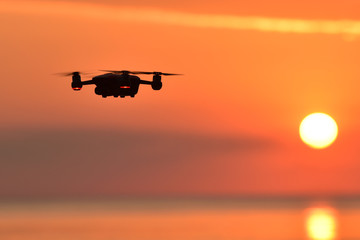 Drone flying in the sunset sky .