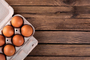 raw chicken eggs in egg box on wooden background