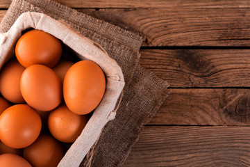 close-up of raw chicken eggs in basket on wooden background