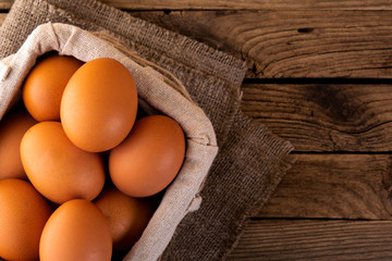 close-up of raw chicken eggs in basket on wooden background
