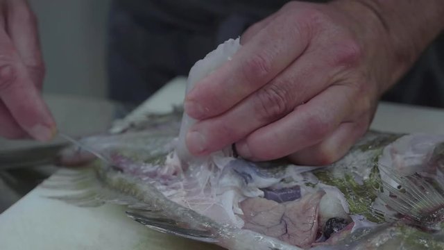 chef che sta sfilettando un pesce per cucinarlo