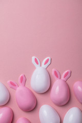 Easter eggs with bunny ears on a pastel pink background