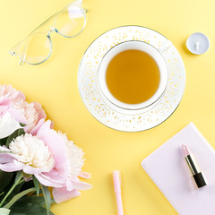 Beautiful cosmetics and flowers flat lay with note book, herbal tea on pastel background.